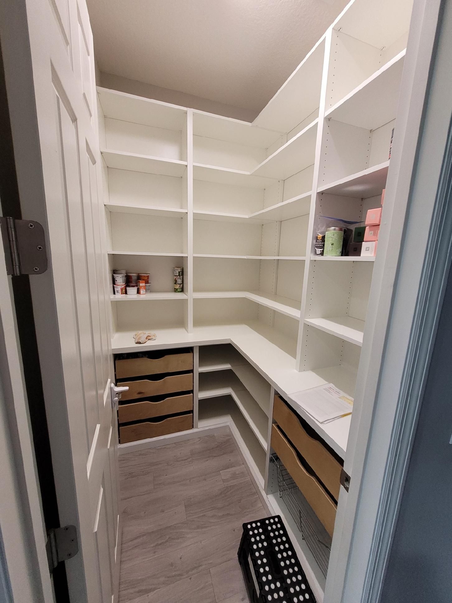 A walk in pantry with lots of shelves and drawers.