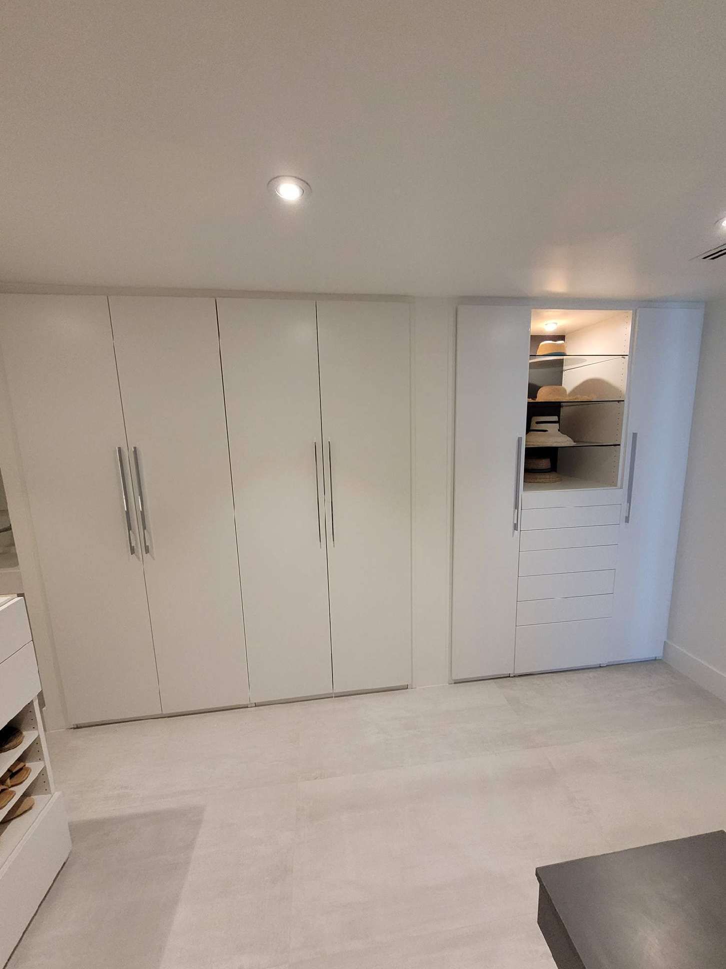 A room with a lot of white cabinets and a table.
