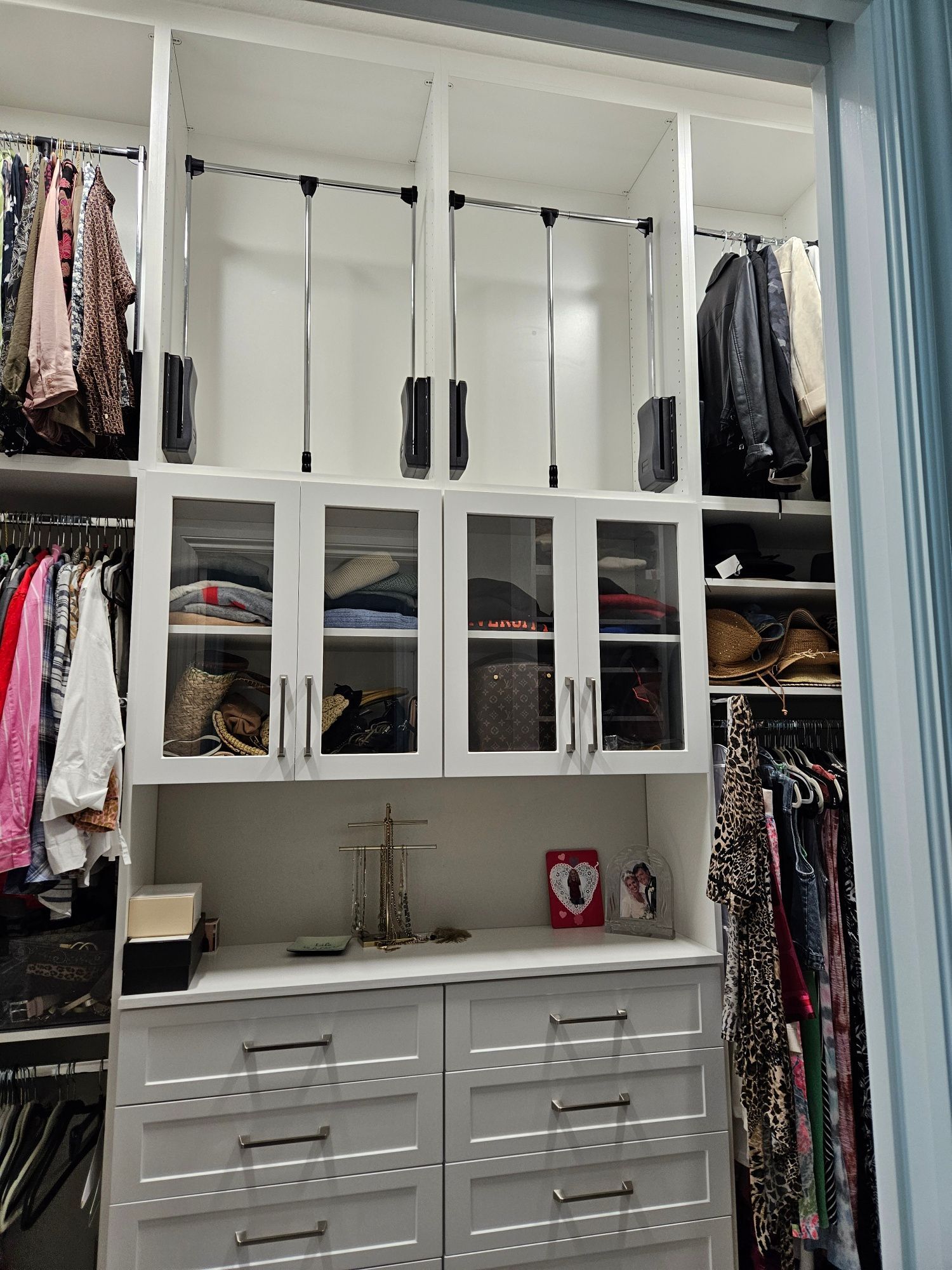 A walk in closet filled with lots of clothes and drawers.