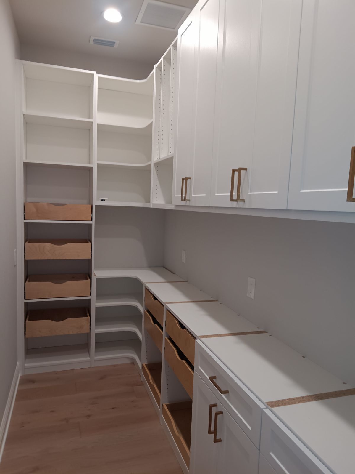 A kitchen with white cabinets and wooden drawers