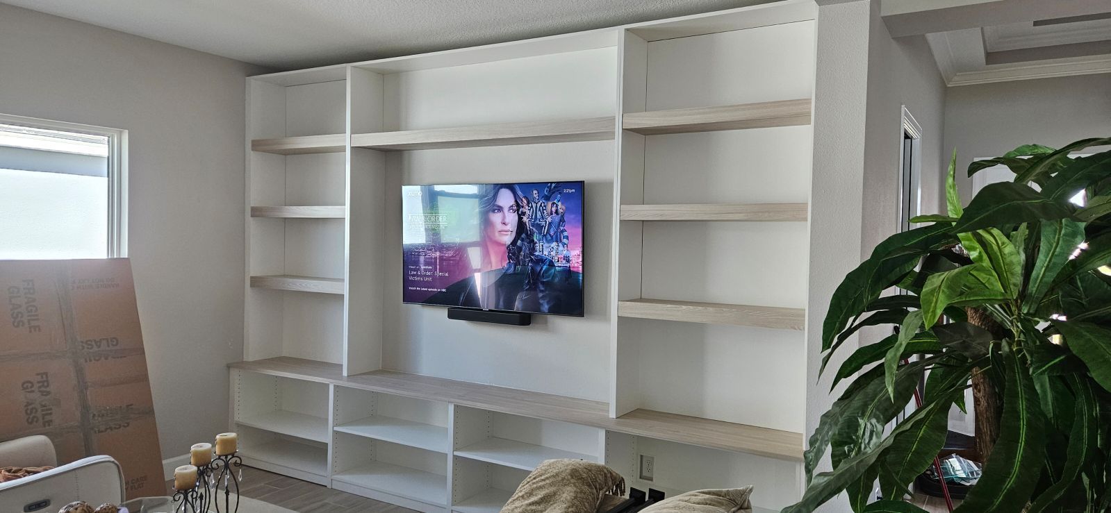 A living room with lots of shelves and a flat screen tv on the wall.