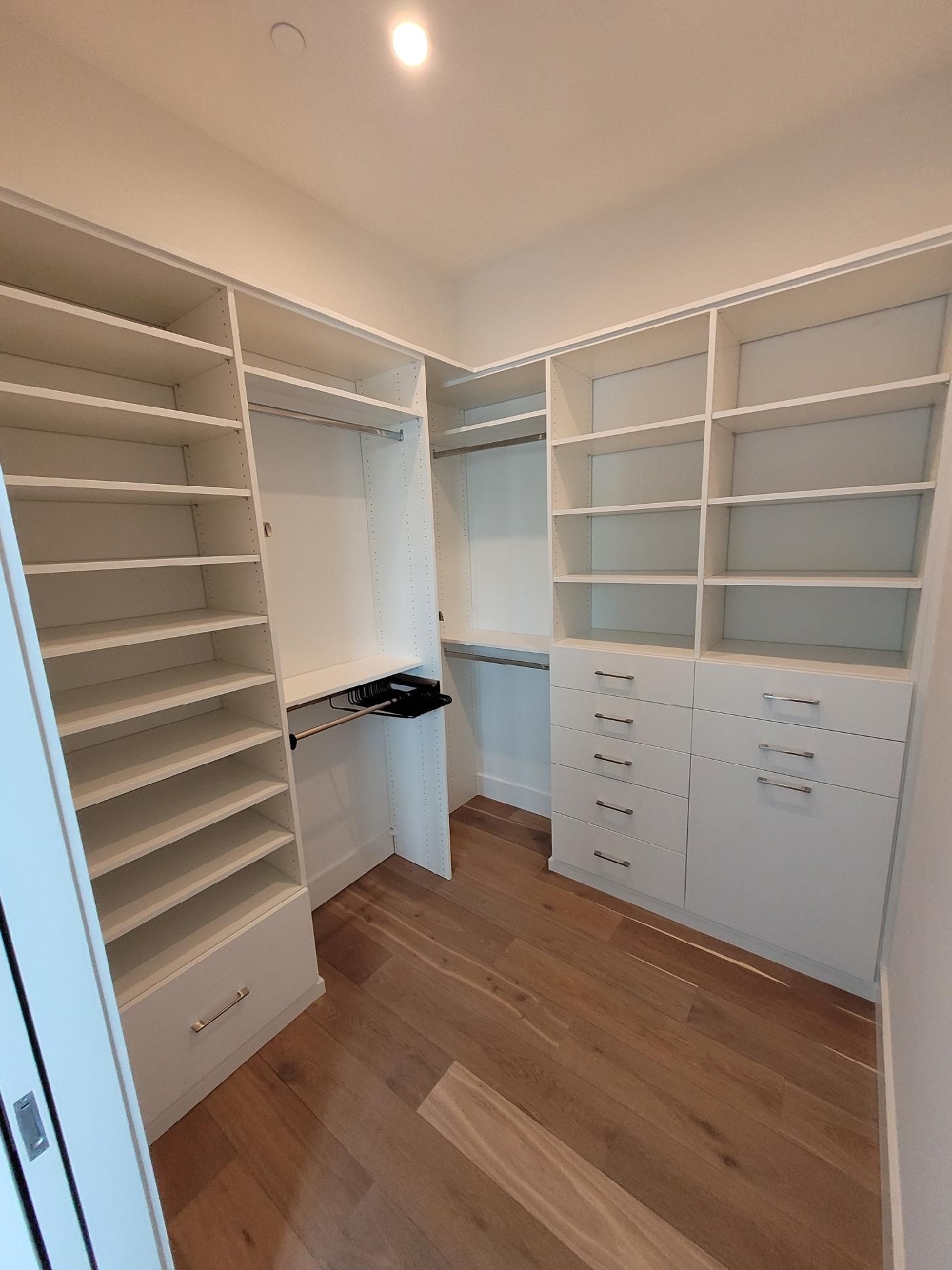 A walk in closet with lots of shelves and drawers.