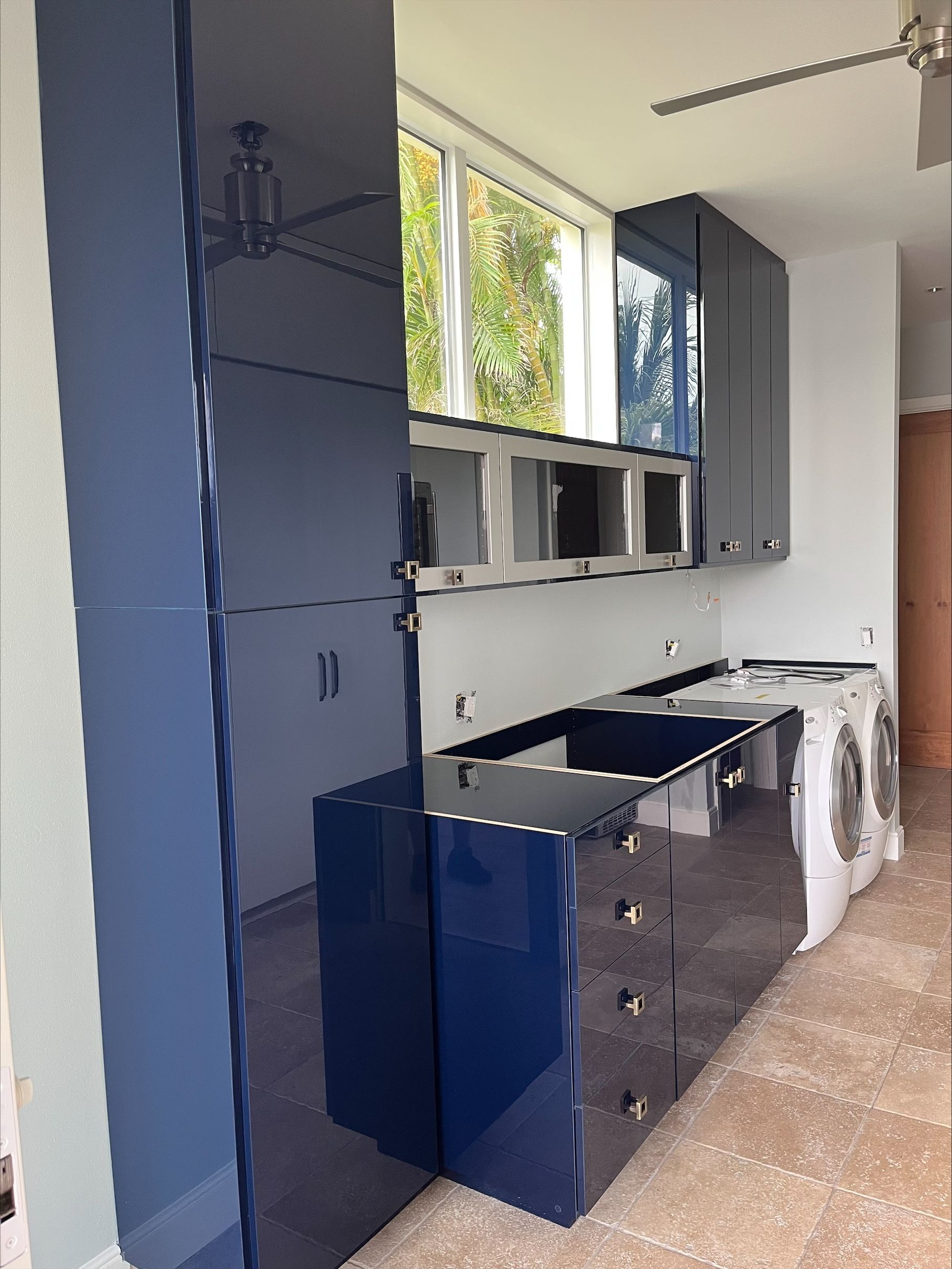 Blue laundry room with cabinetry, washer, dryer, and window.