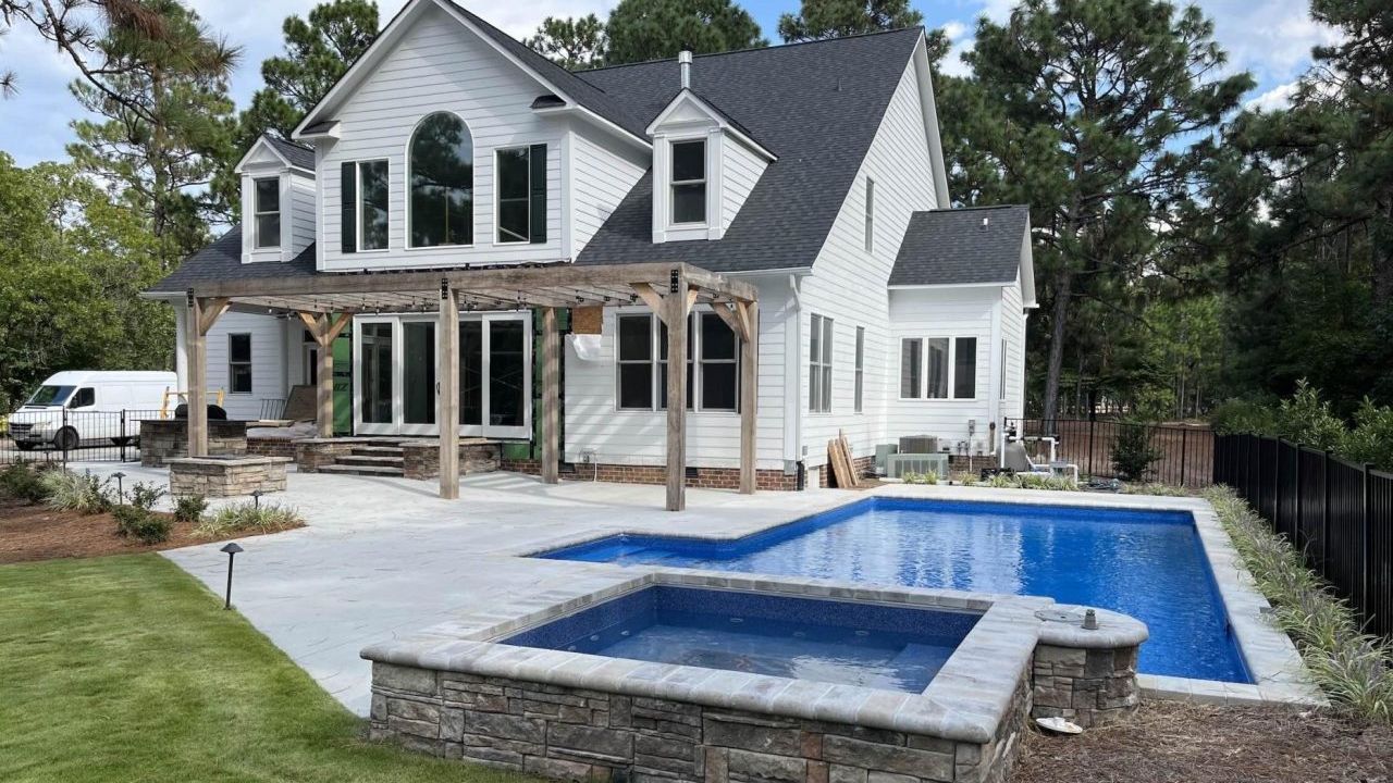 A large white house with a large swimming pool in front of it.