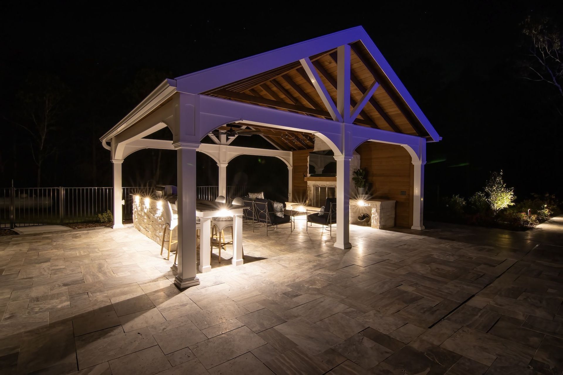 A pavilion is lit up at night with a blue light on the roof