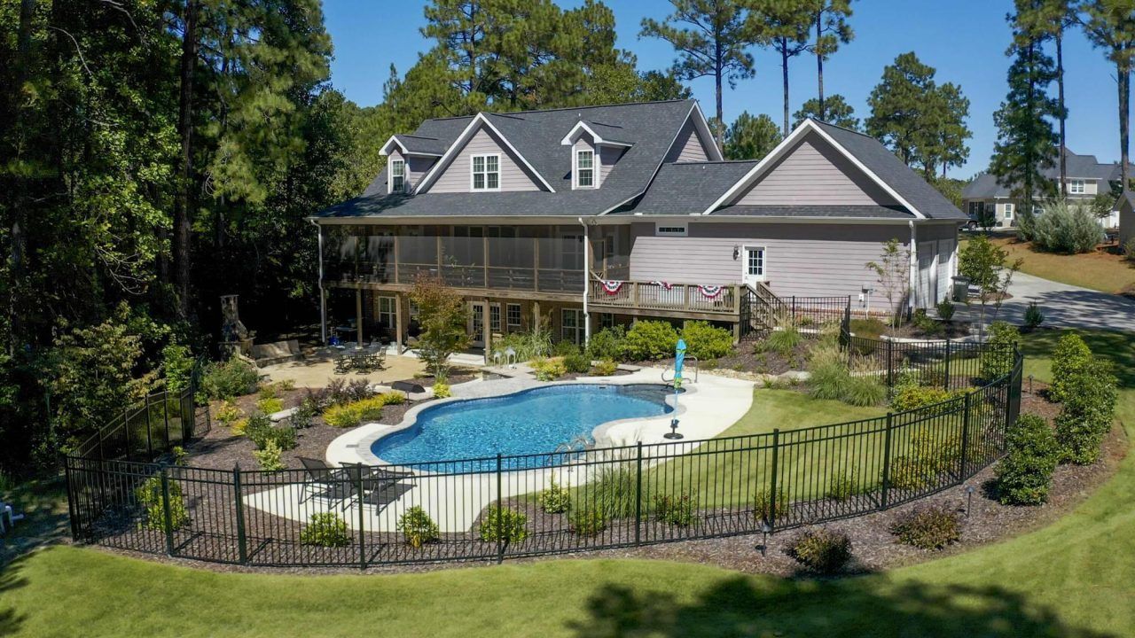 A large house with a large swimming pool in the backyard surrounded by trees.