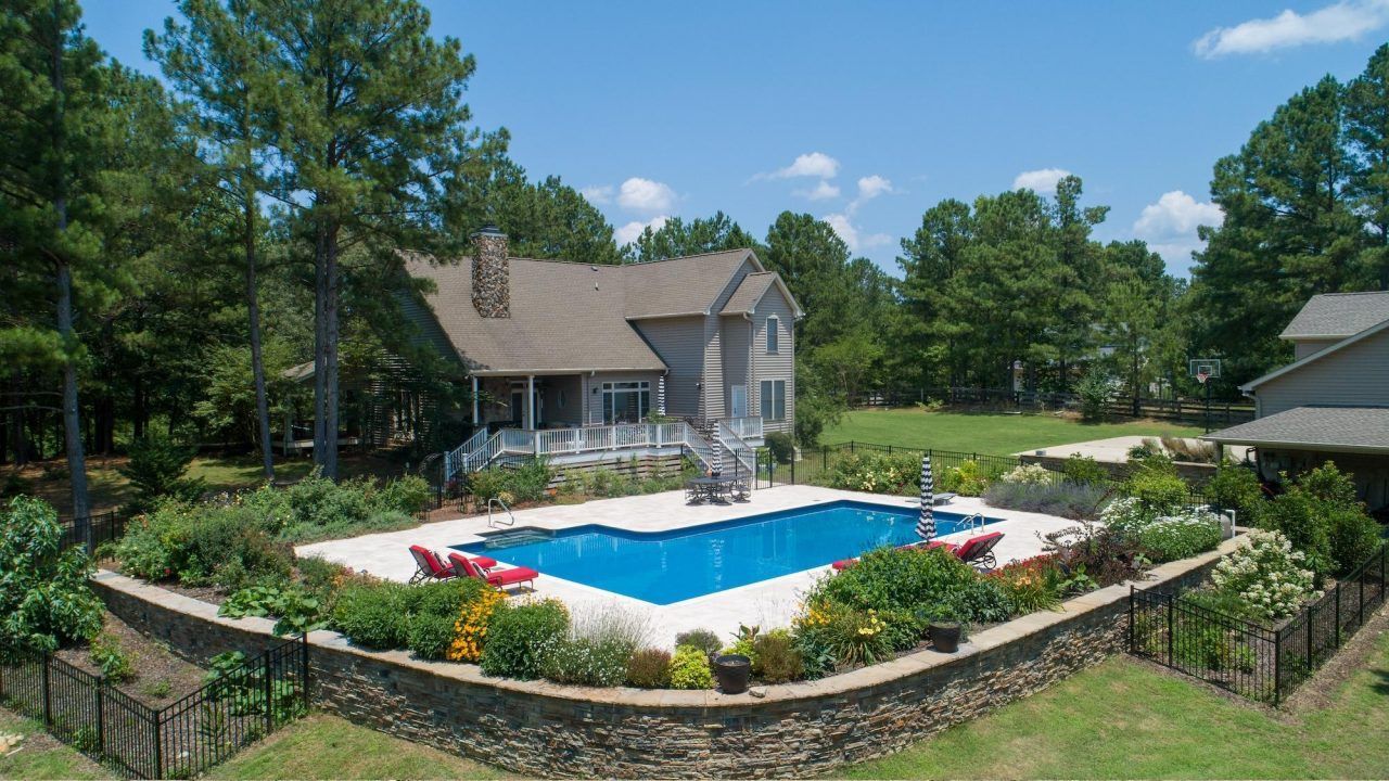 An aerial view of a house with a large swimming pool in the backyard.