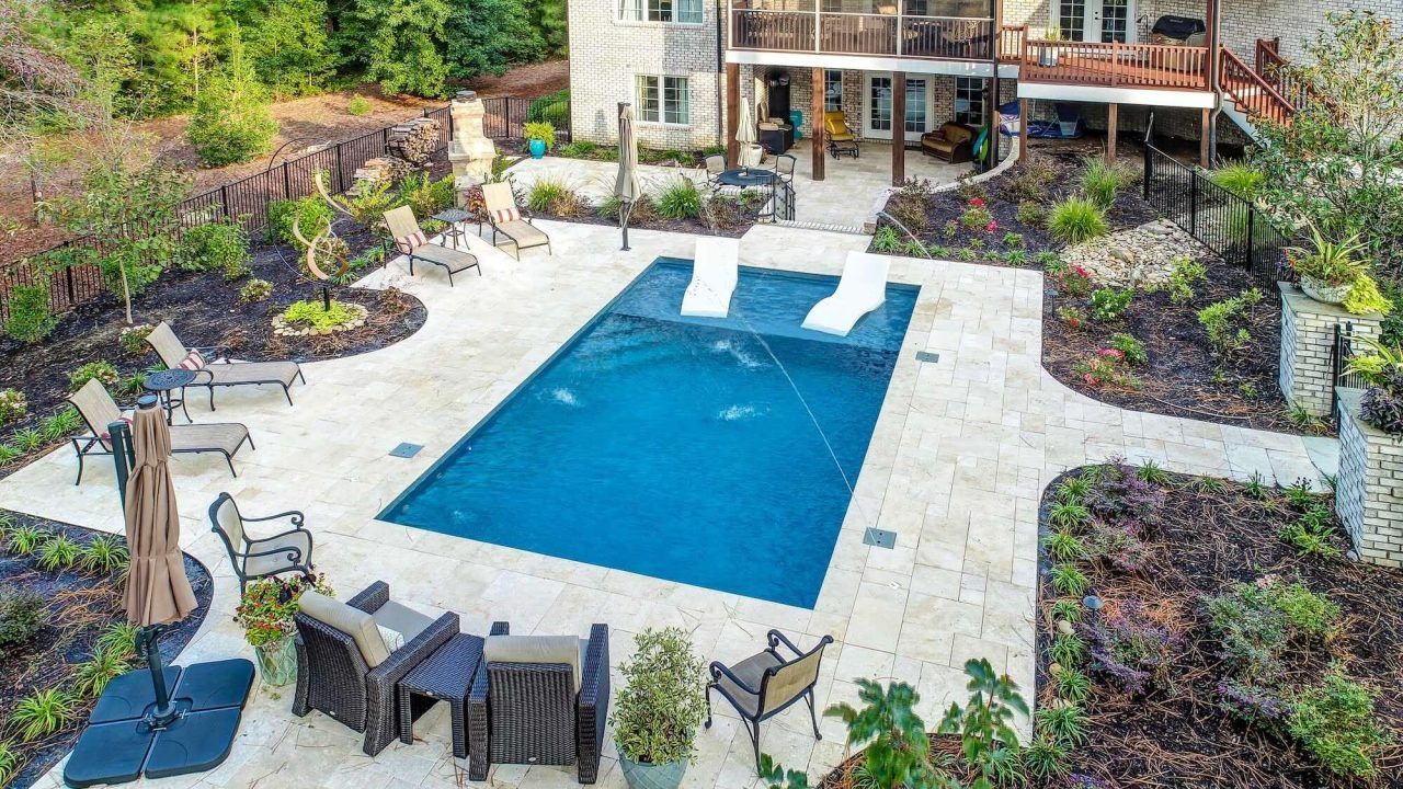 An aerial view of a large swimming pool in the backyard of a house.