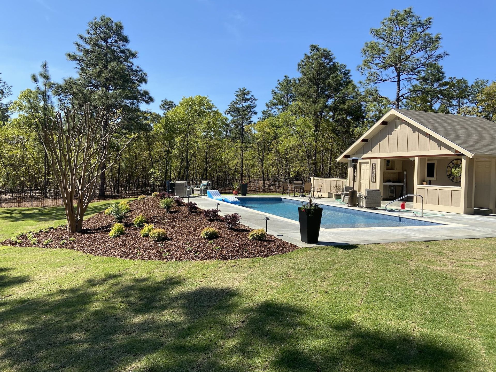 A house with a swimming pool in the backyard surrounded by trees.