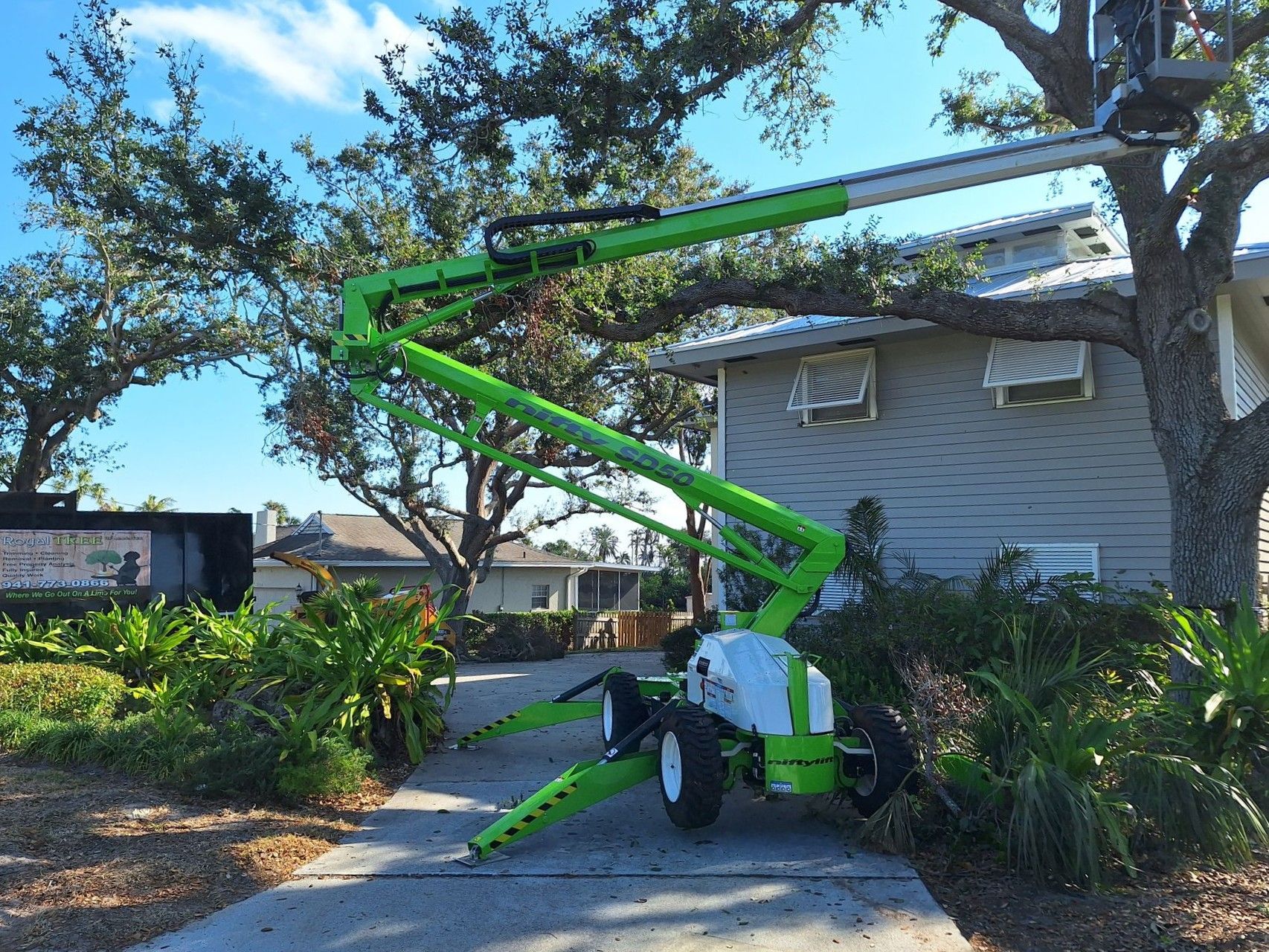 A green and white lift is sitting in front of a house.