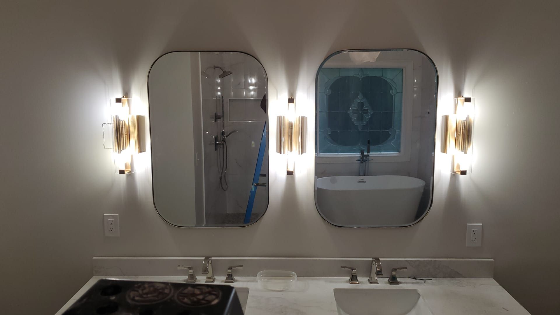 Modern bathroom vanity with double mirrors, wall sconces, and white countertops.