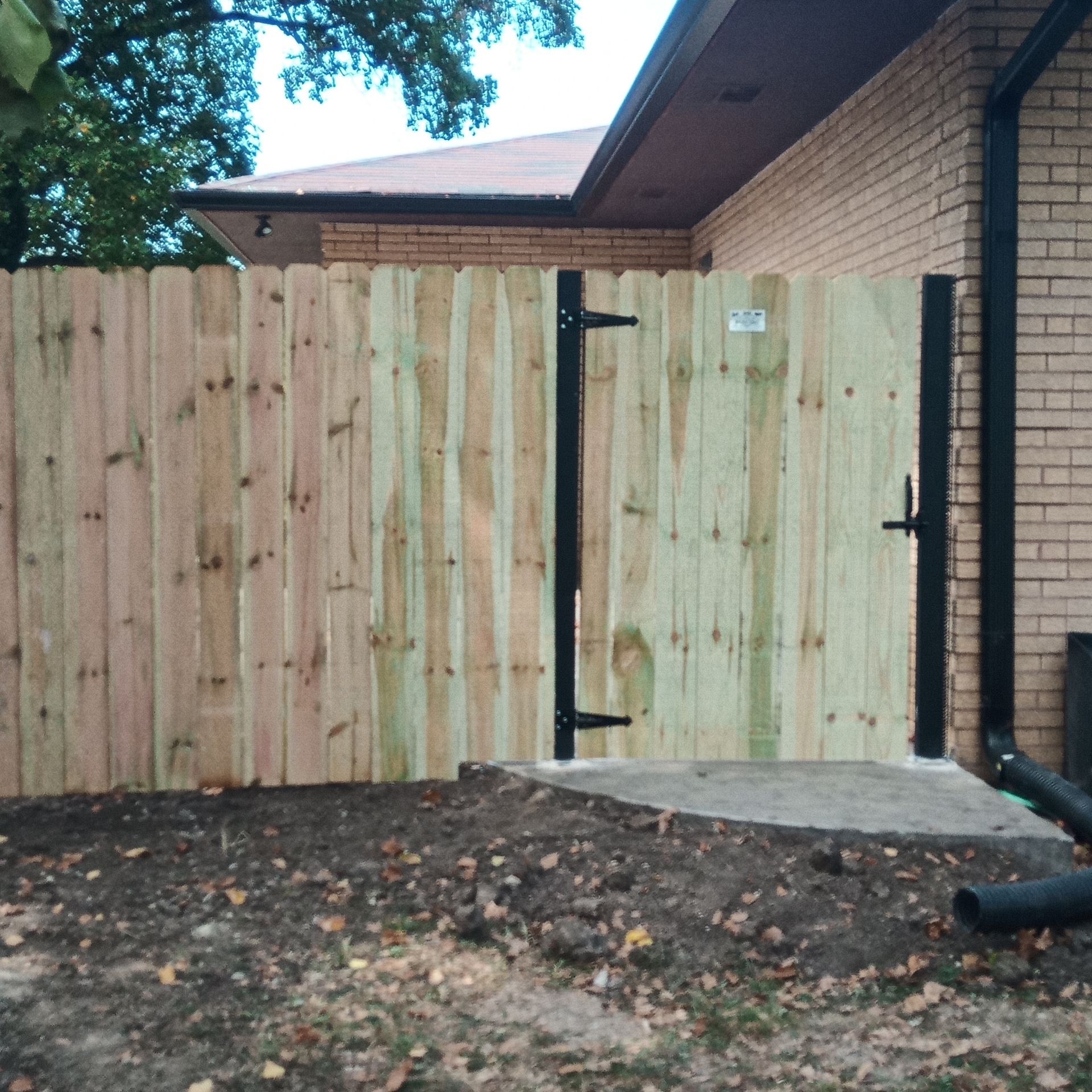 Wooden fence with gate, brick building.