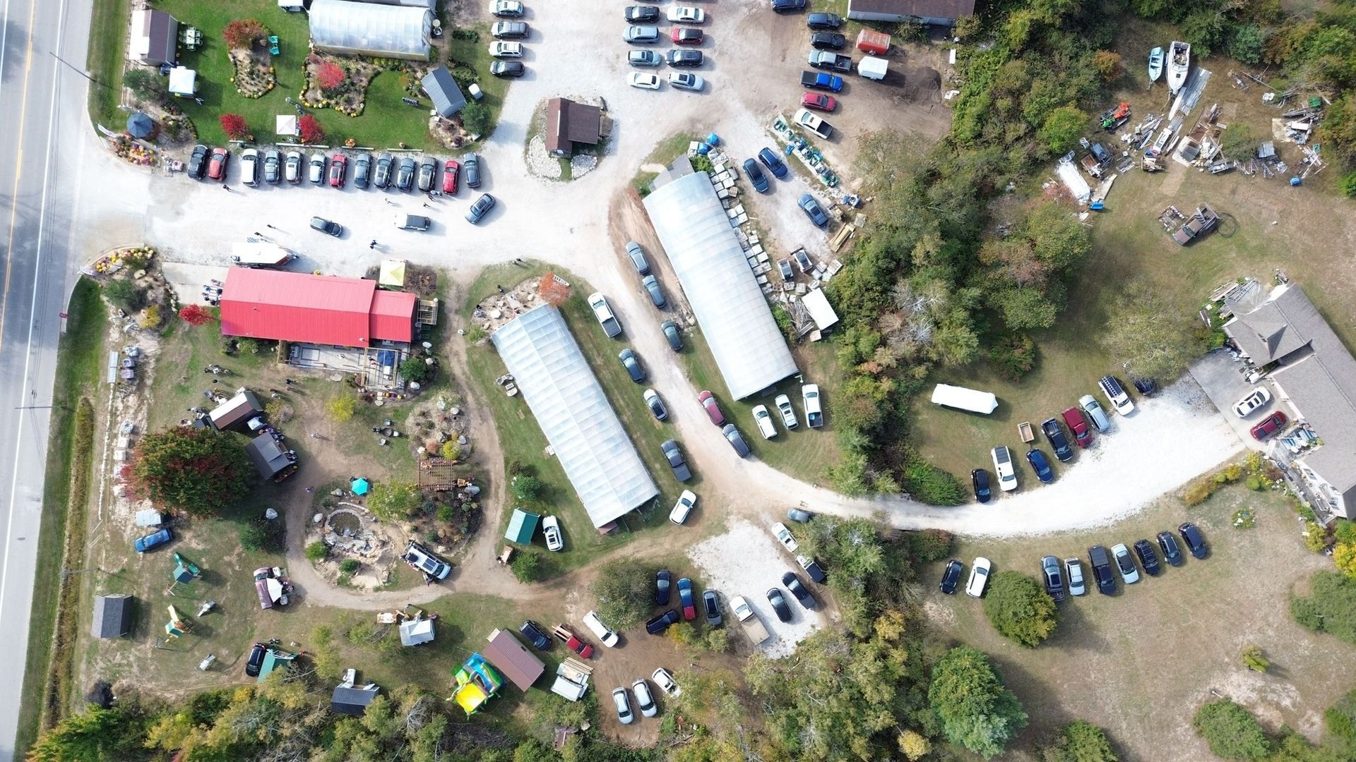Aerial view of a business with many vehicles, buildings, and a road. White and red buildings are visible.