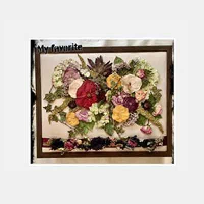 Floral artwork with a variety of dried flowers in a brown frame.