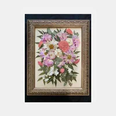 Framed floral arrangement featuring pink, white, and green pressed flowers.