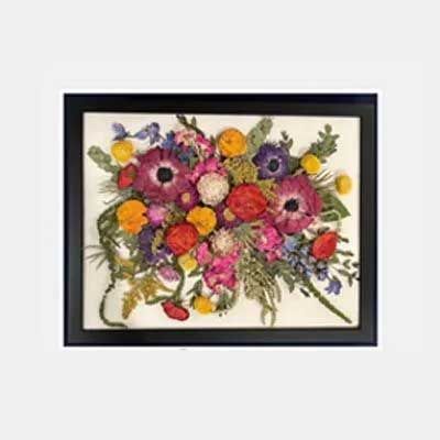Framed pressed flower arrangement with various colorful blooms, including red, pink, yellow, and purple flowers on a cream background.