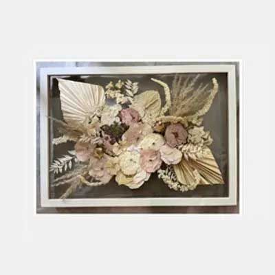 Dried flowers and leaves in a rectangular shadow box frame; neutral tones.