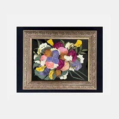Framed dried flower bouquet against a black background. Gold frame with various colorful blooms.