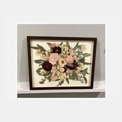 Framed pressed flower bouquet with pink and burgundy blooms on a white background.