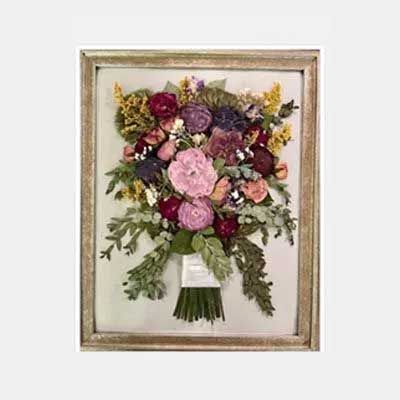 Framed dried flower bouquet; pink, purple, and yellow blossoms with greenery.