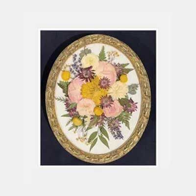 Oval framed floral arrangement with yellow, pink, and purple pressed flowers.