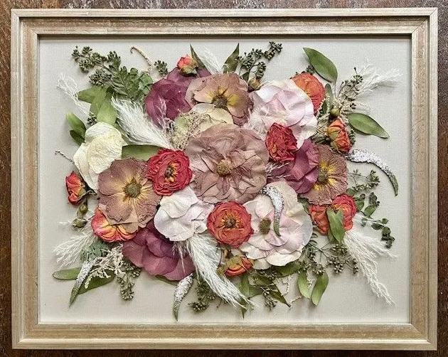 Framed floral arrangement of dried, colorful flowers in shades of red, pink, and cream.