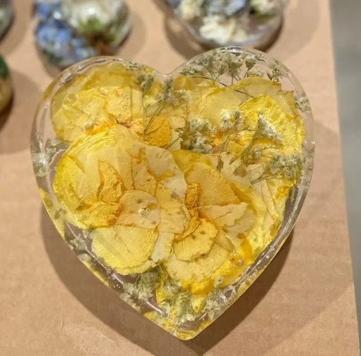 Heart-shaped resin with yellow dried flowers.