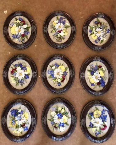 Nine oval framed floral arrangements with blue, yellow, and red flowers.