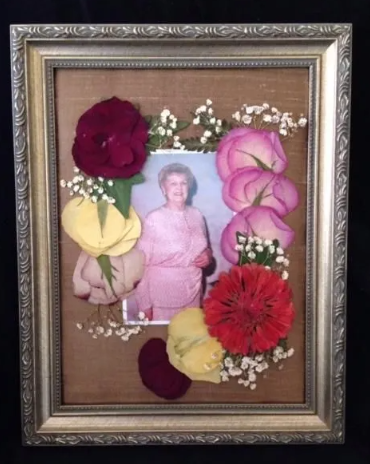 Framed photo with woman surrounded by pressed flowers; burgundy, pink, and yellow.