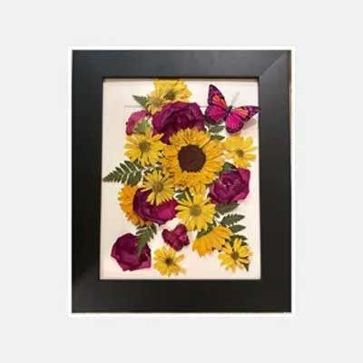 Framed pressed flower art with sunflowers, roses, and a butterfly.