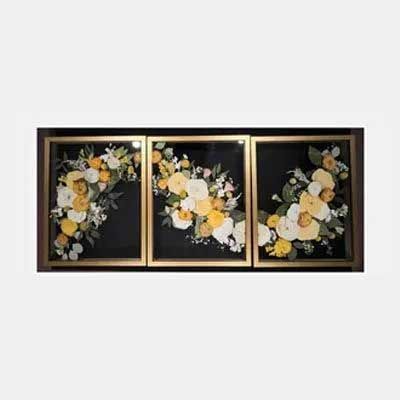 Triptych floral art with yellow, white, and greenery flowers set against a black background with a gold frame.