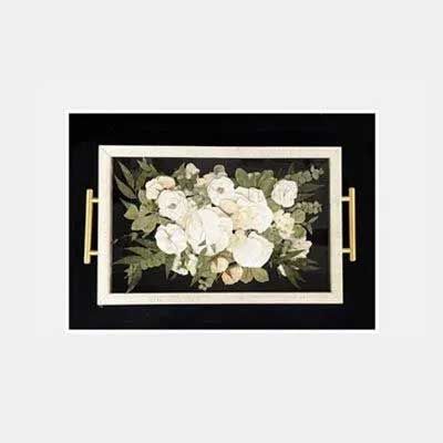 White floral arrangement in a rectangular tray with gold handles, set against a black background.
