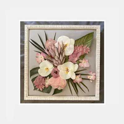 Framed floral arrangement featuring white orchids, pink blooms, and green leaves against a gray background.