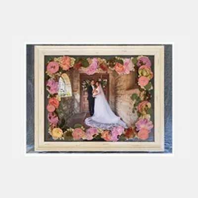 Framed wedding photo with floral accents; couple in front of archway.