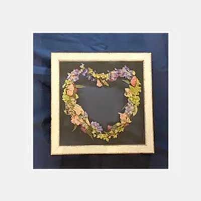 White-framed artwork with a heart-shaped floral arrangement on a dark background.