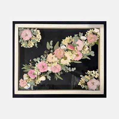 Framed floral arrangement of pink and white flowers on a black background.