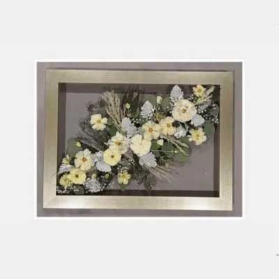 Framed floral arrangement with white and yellow flowers, silver leaves, and gray background.