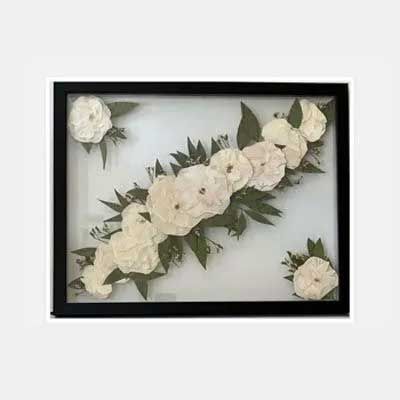 Black framed art piece with white flowers, green leaves on a white background.