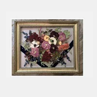 Dried flower bouquet in gold-framed shadow box.