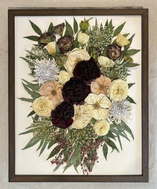 Framed floral bouquet artwork with cream, burgundy, and pale yellow flowers on a beige background.