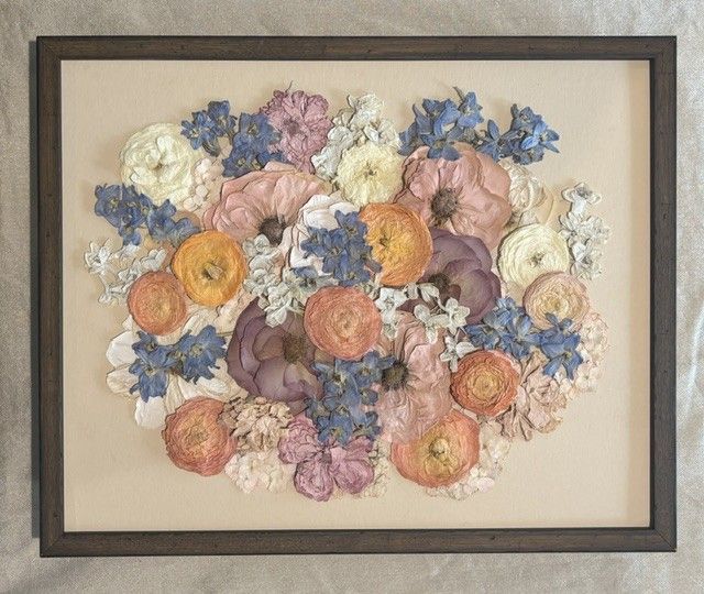Framed floral arrangement with pastel dried flowers in pink, yellow, blue, and white.
