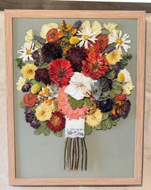 Framed bouquet collage of colorful flowers with a pale green background and ribbon-tied stems.