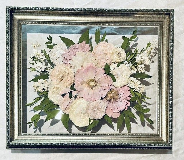 Framed pastel floral bouquet artwork with pink, cream, and white flowers on a blue-gray background.
