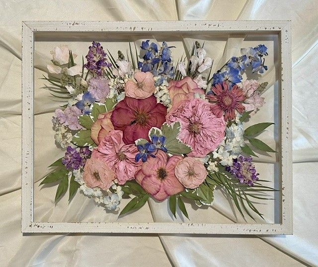 Framed floral arrangement with pink, purple, and blue flowers on a white background.