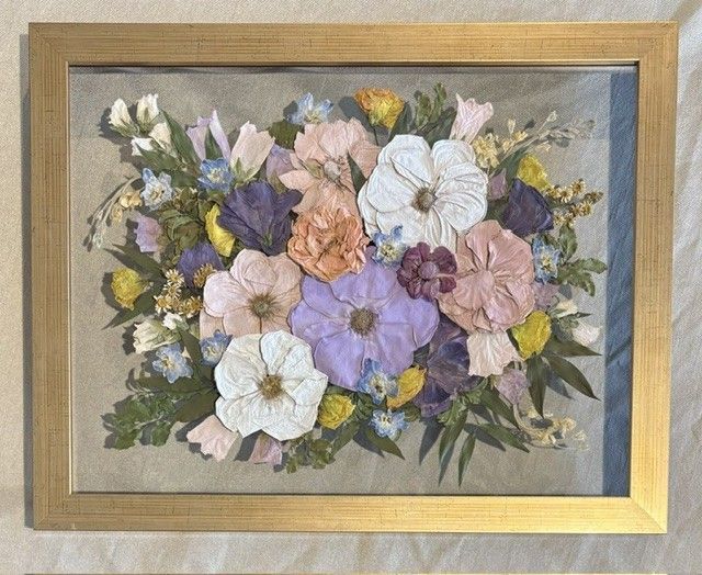 Framed floral bouquet artwork with pastel white, pink, purple, and yellow flowers on a gray background.