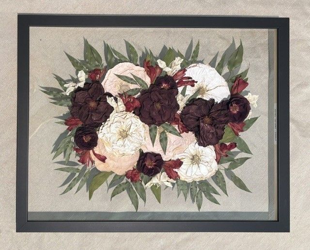 Framed floral wall art with dark burgundy, cream, and green flowers on a beige background.