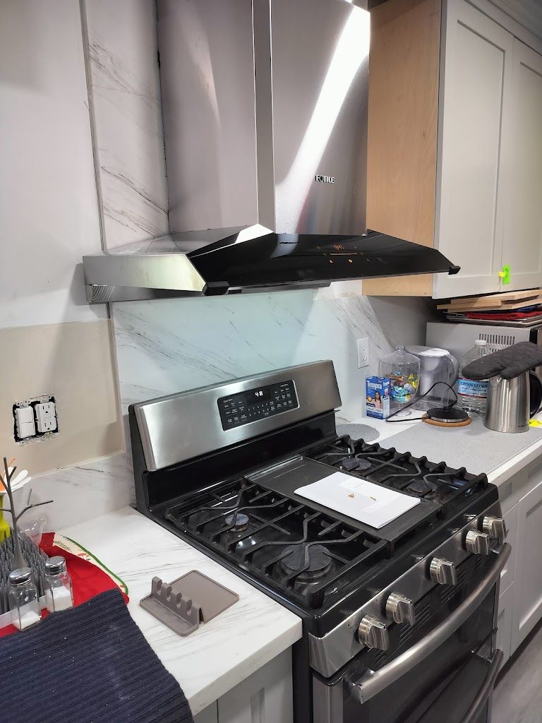 A kitchen with a stove , oven , and hood.