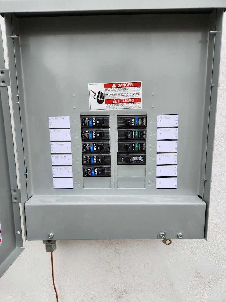 A electrical box is sitting on a wall with the door open.