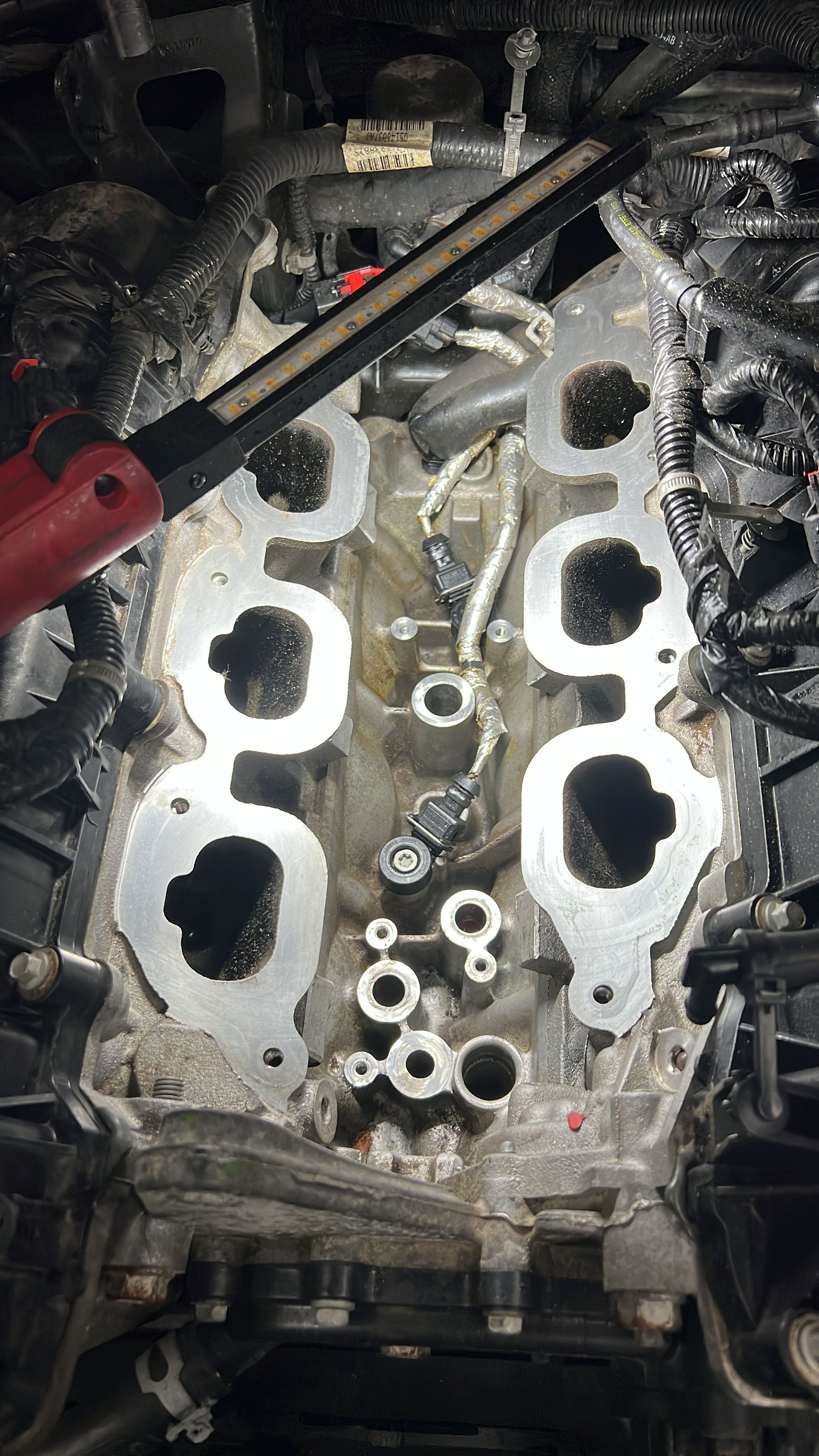 A close up of a car engine with a wrench in it.