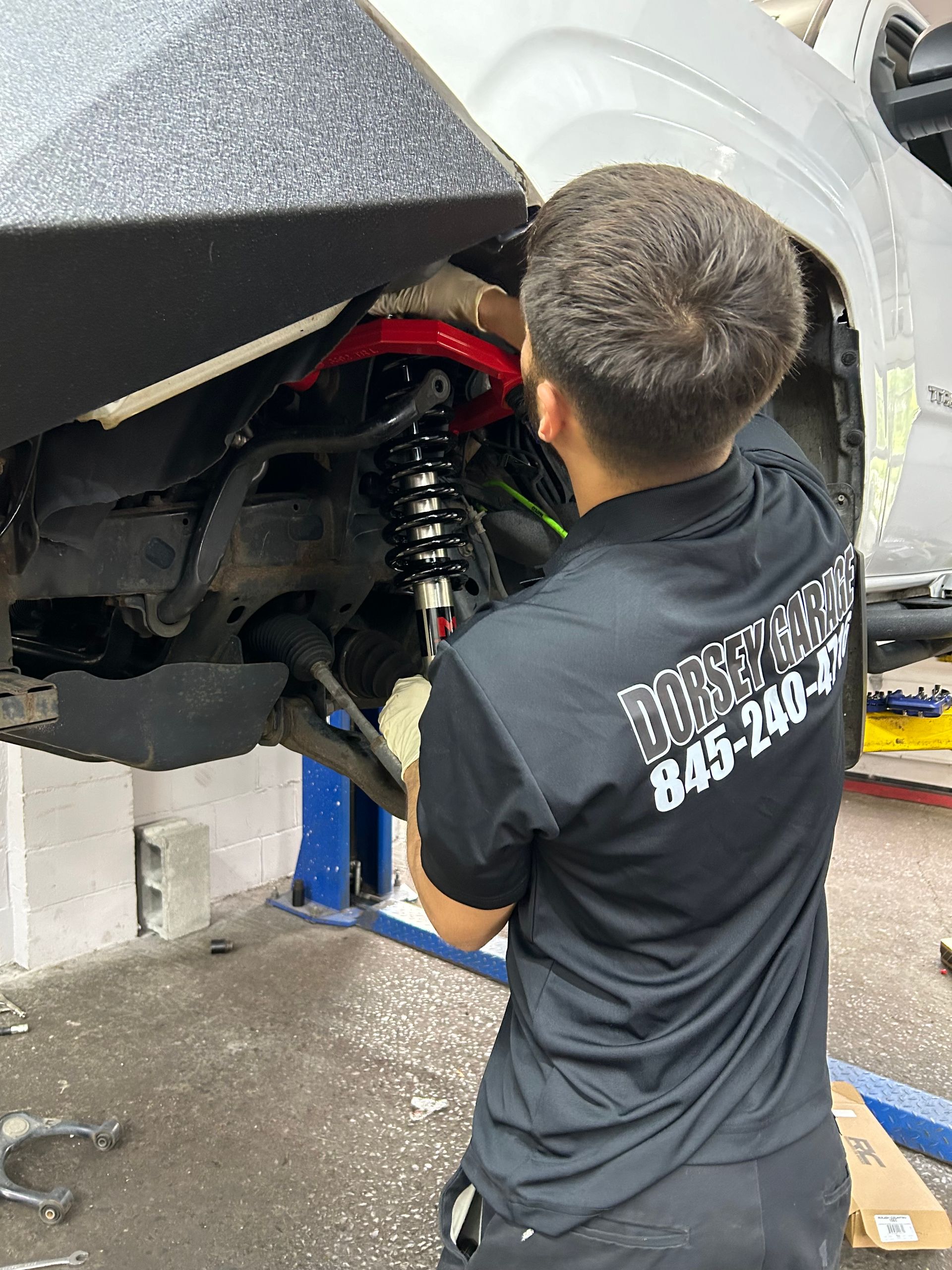 A man in a black shirt is working on a car in a garage.